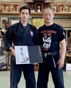 Bujinkan Dojo teacher Nagato Toshiro sensei standing together with Andrius Zaidovas, in hand holding a drawing of Soke Hastumi Masaaki